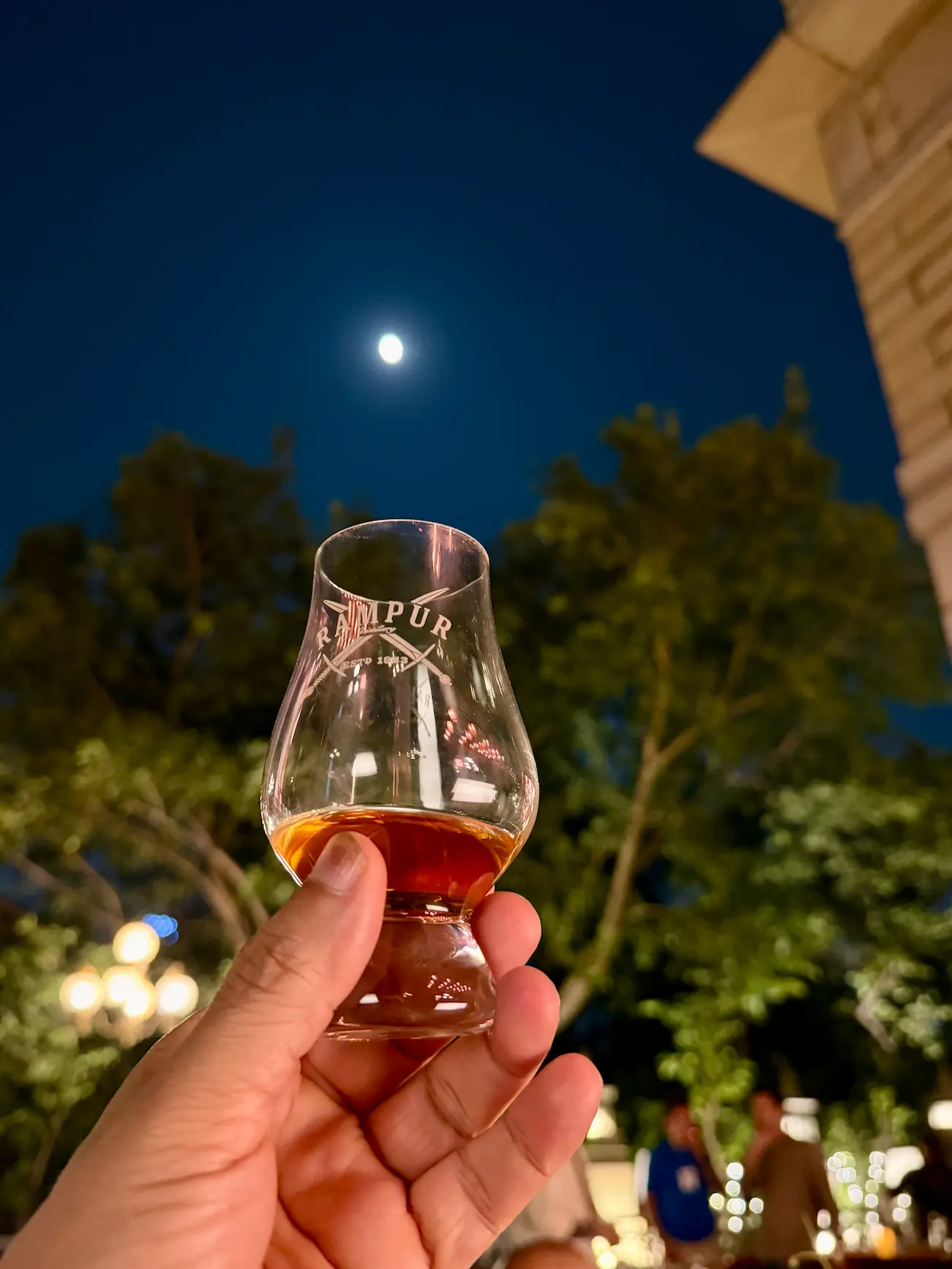 Tasting Virasat whiskey from Rampur Distillery under a moonlit sky 